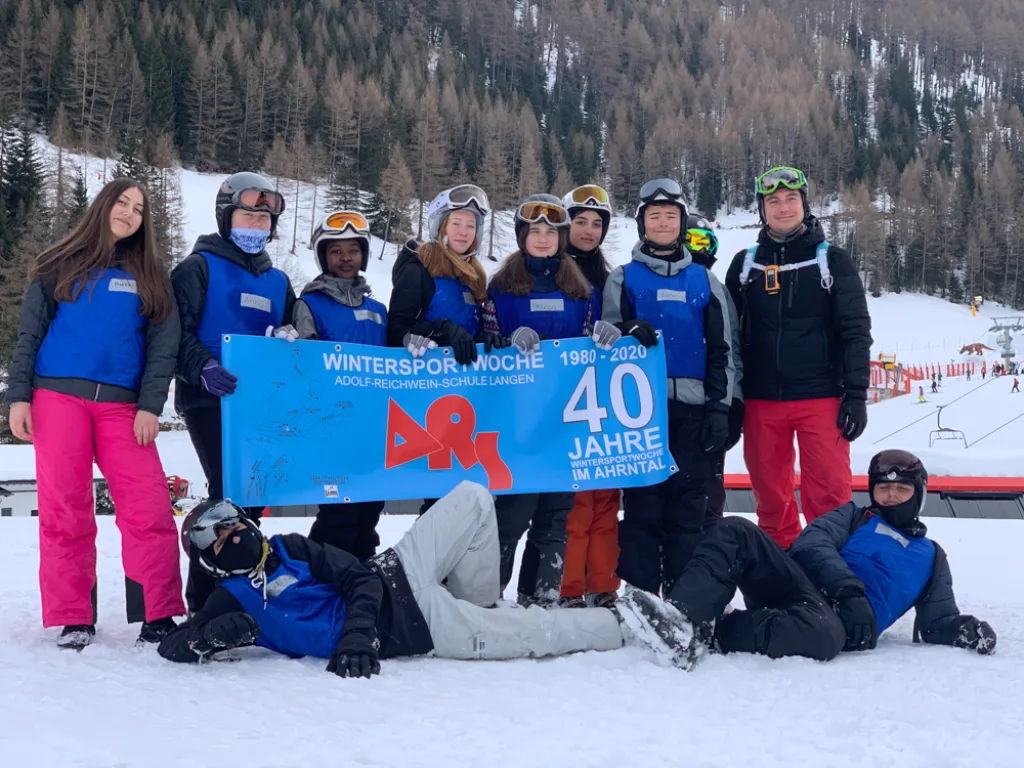 Eine Gruppe hält das Banner „40 Jahre“, einige knien im Schnee davor.
